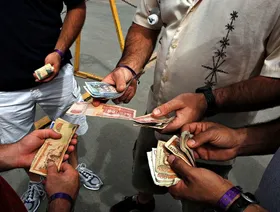 أشخاص يتبادلون أوراقاً نقدية من فئات مختلفة من عملة "البيزو" الدومينيكاني - بلومبرغ