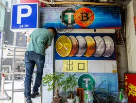 شخص ينزل من سلم أمام شاشة تعرض شعارات لعملات مشفرة خارج مكتب صرافة - بلومبرغ