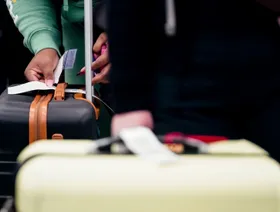 مسافر يلصق بطاقة تعريفية على حقيبة أمتعته - بلومبرغ