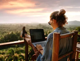 سيدة تعمل عن بعد من على شرفة مطلة على حديقة - المصدر: بلومبرغ