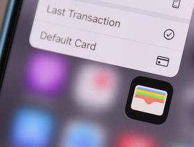 شاشة هاتف ذكي تظهر عليها أيقونة تطبيق المحافظ الرقمية (Apple Wallet)، مع جزء من القائمة الخاصة بالتطبيق والتي تشمل خيارات مثل "أحدث عملية" و"البطاقة الافتراضية" - الشرق/بلومبرغ