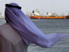 رجل بالزي الوطني الإماراتي ينظر إلى ناقلة نفط راسية في ميناء الفجيرة، الإمارات العربية المتحدة - المصدر: بلومبرغ