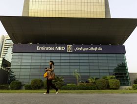 سيدة تمر من أمام المكتب الرئيسي لبنك الإمارات دبي الوطني في دبي، الإمارات العربية المتحدة - المصدر: بلومبرغ