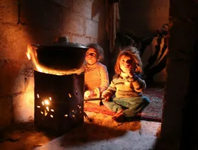 طفلتان تتدفآن حول النار في الغوطة الشرقية قرب دمشق، في 6 يناير 2014؛ حيث كان هذا الجزء من العاصمة وغيره يعاني من نقص حاد في إمدادات الغذاء والوقود، نتيجة الحصار الذي تفرضه القوات الموالية للرئيس بشار الأسد - رويترز