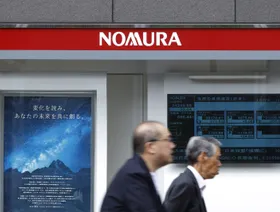 شخصان يعبران من أمام فرع تابع لشركة "نومورا" في طوكيو، اليابان - بلومبرغ