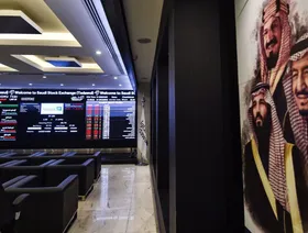 صورة من داخل قاعة في سوق الأسهم السعودية (تداول) فيما تظهر على الجدار الأيمن لوحة فنية تحمل صور مؤسس المملكة العربية السعودية الراحل الملك عبدالعزيز آل سعود، والملك سلمان بن عبالعزيز، وولي عهده الأمير محمد بن سلمان. الرياض، المملكة العربية السعودية - AFP