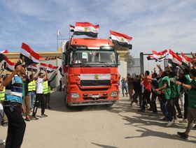 عمال إغاثة مصريون يحتفلون بعودة شاحنة مساعدات إلى مصر عبر معبر رفح الحدودي مع قطاع غزة في 21 أكتوبر 2023 - المصدر: بلومبرغ