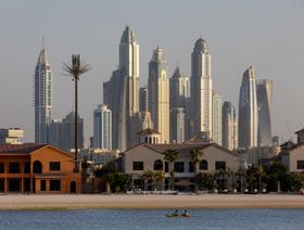 زورق يمر بجانب فلل سكنية مطلة على الواجهة المائية في نخلة جميرا، بينما تظهر ناطحات سحاب سكنية في منطقة مرسى دبي، الإمارات العربية المتحدة - بلومبرغ