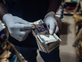 بائع يلبس قفازاً  يعد أوراق نقد نيجيرية في مدينة أبوجا. نيجيريا - المصدر: بلومبرغ