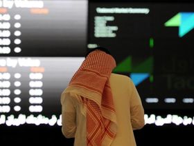 رجل بالزي التقليدي السعودي يتابع حركة الأسهم على لوحة إلكترونية في سوق الأسهم السعودية. الرياض. المملكة العربية السعودية - المصدر: بلومبرغ