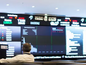 صورة أرشيفية لزائر يطالع أسعار الأسهم المعروضة على شاشة رقمية داخل السوق المالية السعودية - المصدر: بلومبرغ