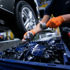 عامل يضع شارات "فورد" على محور العجلات الخاصة بسيارة "فورد فوكس" - المصدر: بلومبرغ