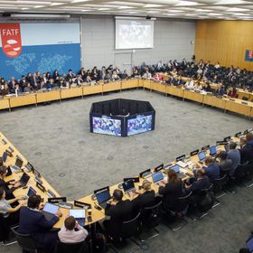 اجتماع لمجموعة العمل المالي بمشاركة ممثلين من مختلف الدول، حيث يجلس المشاركون حول طاولة مستديرة وأمامهم حواسيب وشاشات كبيرة - بلومبرغ