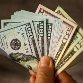 يد تحمل مجموعة من الأوراق النقدية لعملة الدولار الأميركي ذات فئات متنوعة - المصدر: بلومبرغ