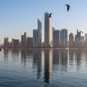 طيور تحلق فوق المياه أمام مبانٍ شاهقة في أفق مدينة أبوظبي، الإمارات - بلومبرغ