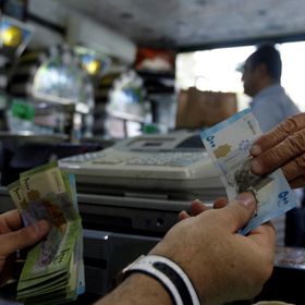 زبون يدفع ثمن مشترياته بالليرة السورية داخل متجر للحلويات في دمشق، سوريا (صورة غير مؤرخة) - رويترز 