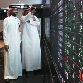 رجلان ينظران إلى لوحة إلكترونية تعرض أسعار الأوراق المالية داخل سوق الأسهم في العاصمة السعودية الرياض (صورة أرشيفية) - المصدر: بلومبرغ