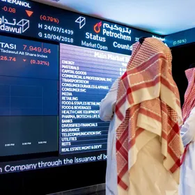 شخصان يطلعان بيانات أسعار الأسهم على لوحة معلومات إلكترونية في سوق الأسهم السعودية 'تداول' - صورة أرشيفية - المصدر: بلومبرغ