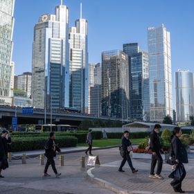 مارة يعبرون الشارع وفي الخلفية تظهر المباني الشاهقة في العاصمة الصينية بكين - بلومبرغ
