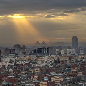صورة تظهر مباني سكنية وتجارية في مدينة القاهرة، وفي الخلفية أهرامات الجيزة، مصر. - المصدر: بلومبرغ