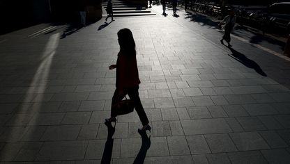امرأة تسير بالقرب من مجمع روبونجي هيلز في طوكيو، اليابان - المصدر: بلومبرغ