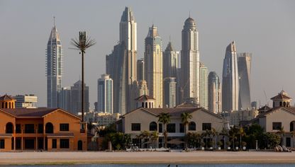 زورق يمر بجانب فلل سكنية مطلة على الواجهة المائية في نخلة جميرا، بينما تظهر ناطحات سحاب سكنية في منطقة مرسى دبي، الإمارات العربية المتحدة - بلومبرغ