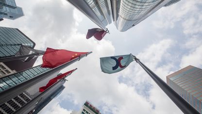 علم شركة "هونغ كونغ اكستشينجز اند كليرينغ"، على اليمين، والعلم الصيني، إلى اليسار، يرفرفان خارج مجمع "إكستشينج سكوير" في هونغ كونغ، الصين - بلومبرغ