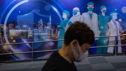 أحد الأشخاص يسير أمام لوحة جدارية تصور عمال الرعاية الصحية في هونغ كونغ.. مازالت الصين تشدّد الإجراءات ضمن حملة "صفر كوفيد" - المصدر: بلومبرغ