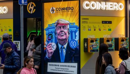 صورة كرتونية للرئيس الأميركي دونالد ترمب مع عملات مشفرة أمام البيت الأبيض معروضة في متجر "كوين هيرو" في هونغ كونغ، الصين، يوم الاثنين 20 يناير 2025 - بلومبرغ