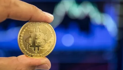 شخص يعرض قطعة رمزية تحمل شعار العملة المشفرة "بتكوين" - المصدر: بلومبرغ