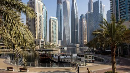 مشاة يمرون عبر المارينا، وفي الخلفية ناطحات سحاب سكنية وتجارية بمنطقة دبي مارينا، دبي - المصدر: بلومبرغ