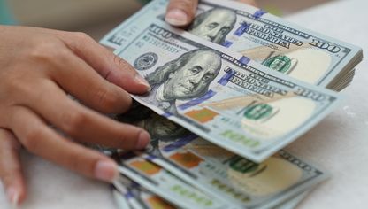 موظف يعد أوراقاً نقدية من الدولار الأميركي في مكتب صرافة. - بلومبرغ