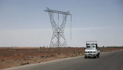 سيارة تمر بجانب برج لنقل الكهرباء عالي الجهد، حيث تم قطع الكابلات وسرقتها، بالقرب من دمشق، سوريا. 26 مايو 2025 - رويترز