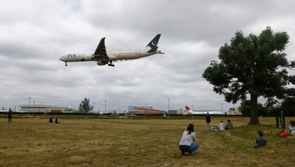 أشخاص  يتابعون حركة طائرة ركاب، تديرها شركة الخطوط الجوية الدولية الباكستانية، وهي بصدد الهبوط بمطار هيثرو في لندن، المملكة المتحدة - المصدر: بلومبرغ