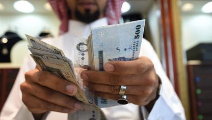 شخص يعد أوراقاً مالية من فئة 500 ريال سعودي - المصدر: بلومبرغ