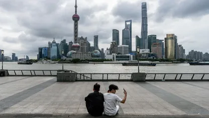 شخصان يجلسان أمام مباني حي لوجياتسوي المالي، منطقة بودونغ، شنغهاي، الصين - بلومبرغ