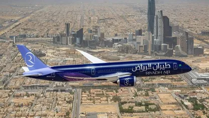 طائرة تحمل شعار "طيران الرياض" تحلق بسماء العاصمة السعودية، ويبدو بالأفق مركز الملك عبدالله المالي - المصدر: بلومبرغ
