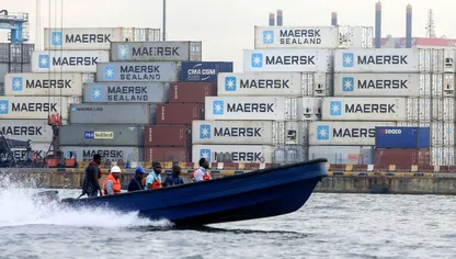 أشخاص على متن قارب يمر بحاويات بمنطقة لادول للتجارة الحرة في لاغوس، نيجيريا - المصدر: بلومبرغ