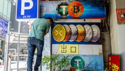 شخص ينزل من سلم أمام شاشة تعرض شعارات لعملات مشفرة خارج مكتب صرافة - بلومبرغ