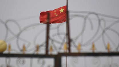 علم الصين خلف أسلاك شائكة - المصدر: أ.ف.ب/غيتي إيمجز