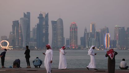 مواطنون ومقيمون يتنزهون عند كورنيش الدوحة فيما تبدو في الأفق ناطحات السحاب في العاصمة القطرية - المصدر: بلومبرغ