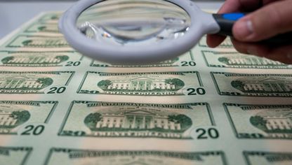 خبير يتفحص أوراقاً نقدية فئة 20 دولار أميركي بعد الطباعة - بلومبرغ