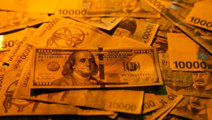 أوراق نقدية من الوون الكوري الجنوبي إلى جانب ورقة من فئة 100 دولار أميركي - بلومبرغ