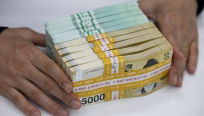 شخص يمسك برزم من الأوراق النقدية لعملة الوون الكورية الجنوبية فئة 5000  - المصدر: بلومبرغ