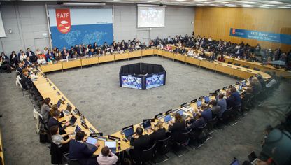 اجتماع لمجموعة العمل المالي بمشاركة ممثلين من مختلف الدول، حيث يجلس المشاركون حول طاولة مستديرة وأمامهم حواسيب وشاشات كبيرة - بلومبرغ