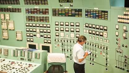 موظف يحمل جهازاً لوحياً في غرفة التحكم في محطة "باكس" للطاقة النووية، بالمجر - bloomberg