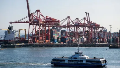 قارب يمر بمحطة حاويات موانئ دبي العالمية في ميناء فانكوفر، كندا - بلومبرغ