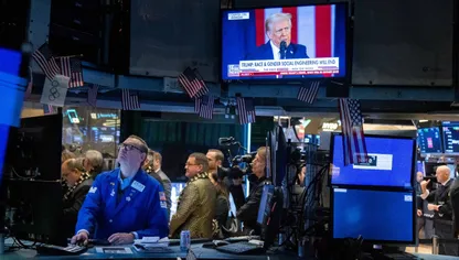 متداولون في بورصة نيويورك يتابعون أداء الأسهم وشاشة تعرض كلمة الرئيس الأميركي دونالد ترمب - بلومبرغ