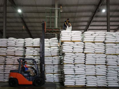 عامل يفرغ أكياس مكدسة من الأرز الأبيض المستورد - المصدر: بلومبرغ