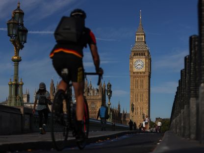 مشاة وراكبو دراجات يعبرون جسر وستمنستر بالقرب من مجلسي البرلمان في لندن، المملكة المتحدة - المصدر: بلومبرغ